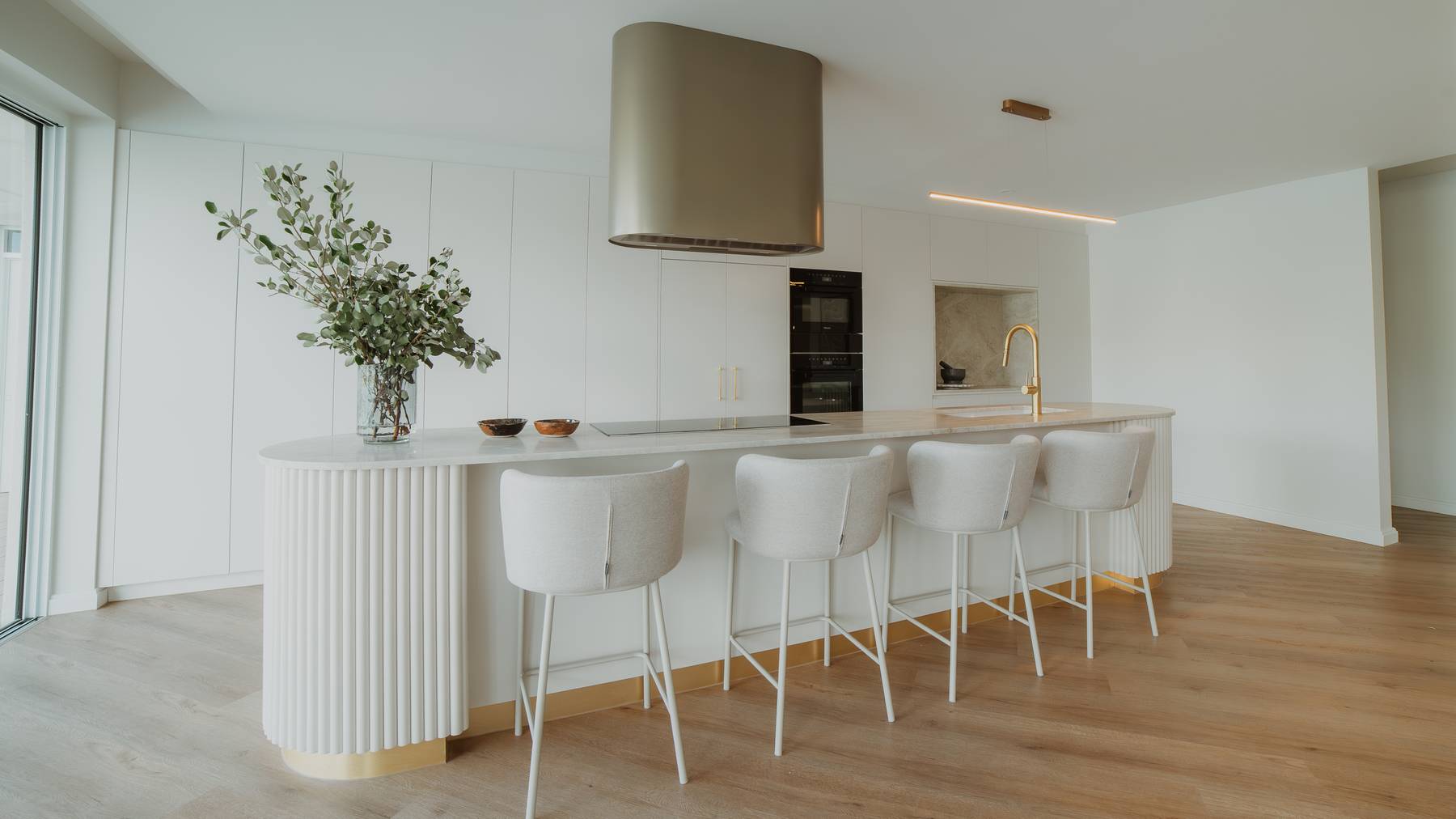 Wide view of a modern kitchen featuring a sleek island with stylish kitchen stools