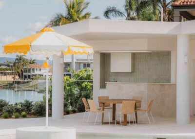 View across the pool into a modern alfresco bar area with stylish seating