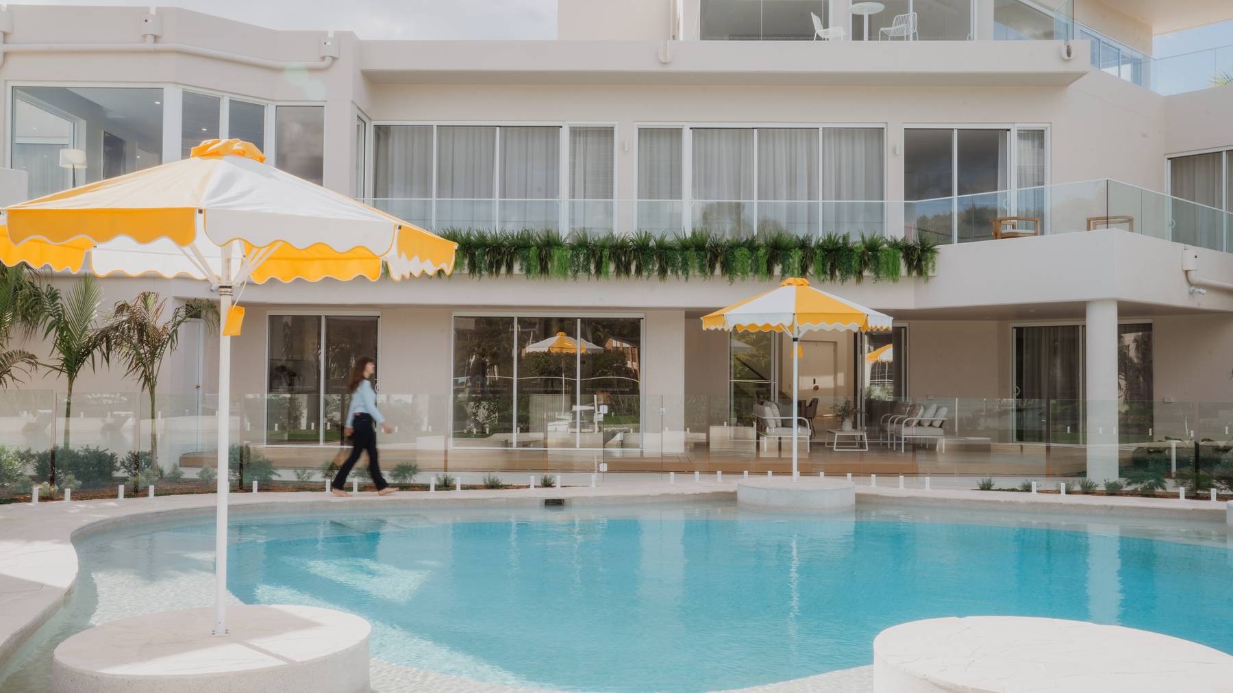 Young woman walking along the edge of a modern pool surrounded by elegant landscaping