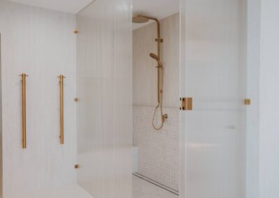 Reeded glass shower surround with elegant brass tapware in a modern bathroom