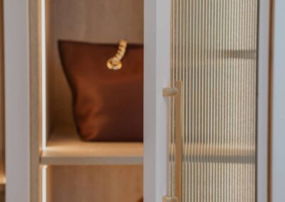 Fluted glass door opened to reveal a stylish handbag inside a modern interior